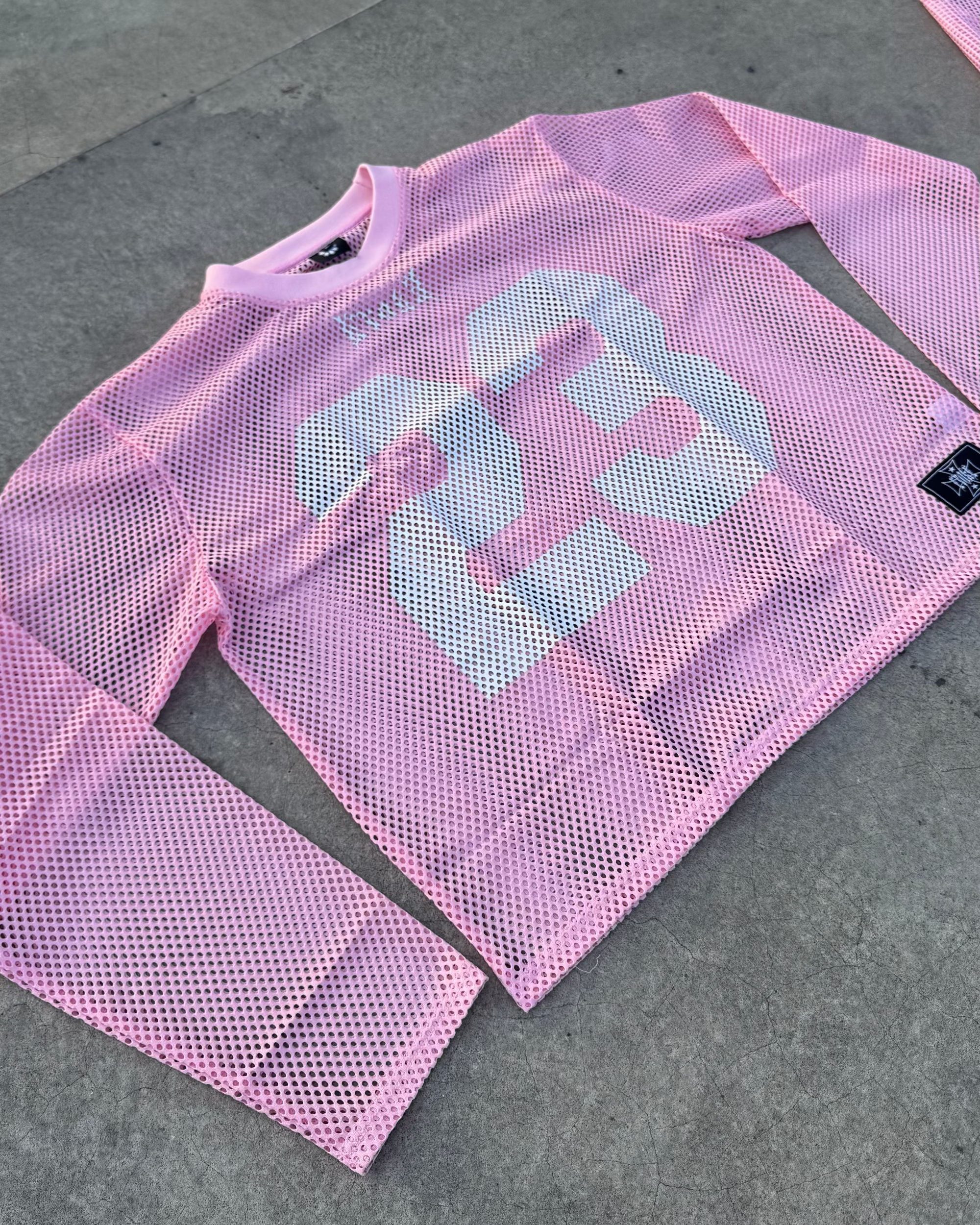 Pink mesh long-sleeve shirt on a concrete surface