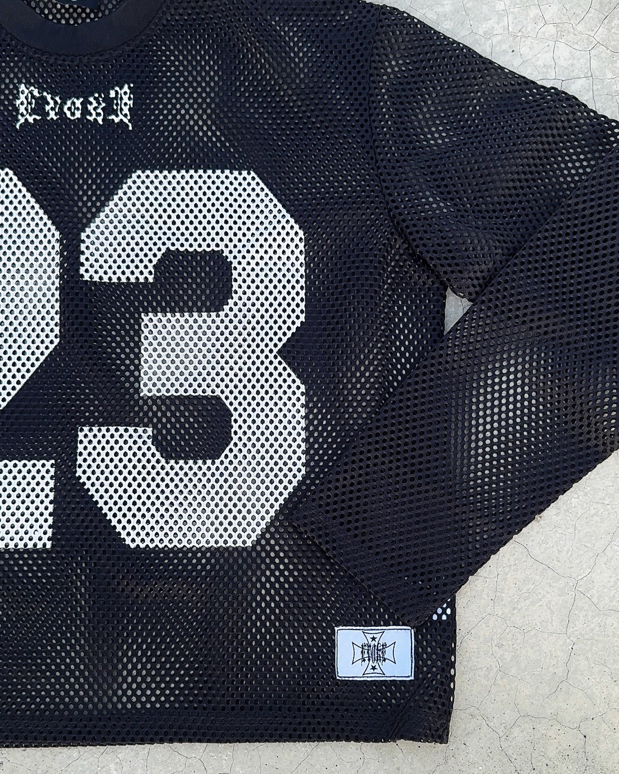 Black mesh jersey with number 23 on a textured surface