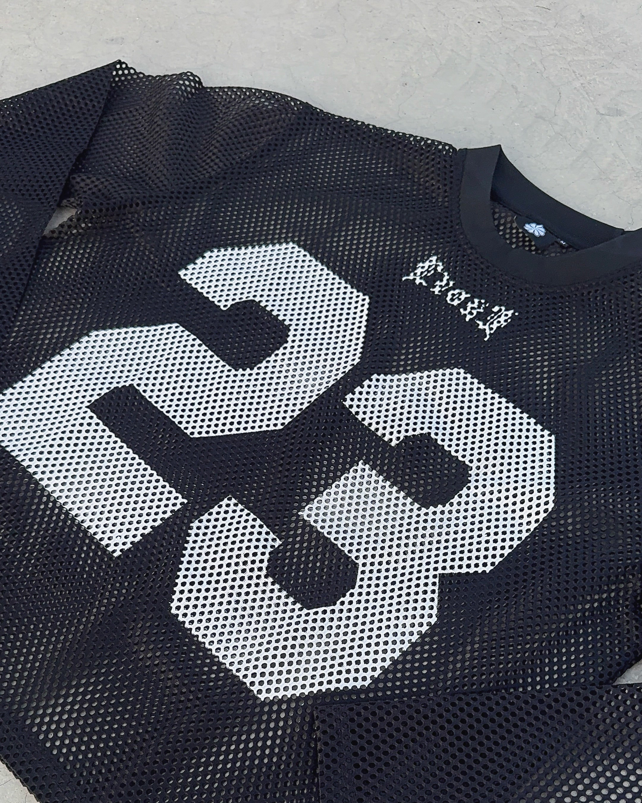 Black sports jersey with white number 23 on a concrete surface