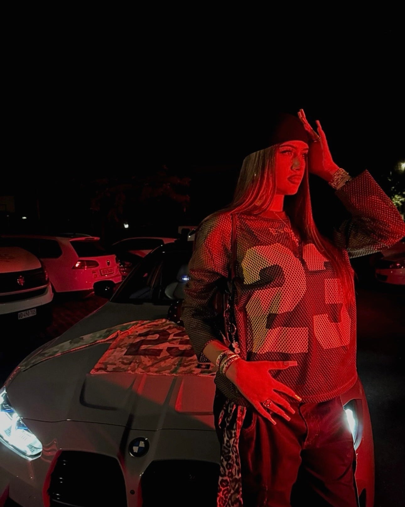 Person standing next to a car with red lighting in a dark setting